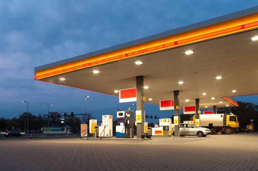 Petrol station forecourt with fuel pumps under a large white canopy on a sunny day
